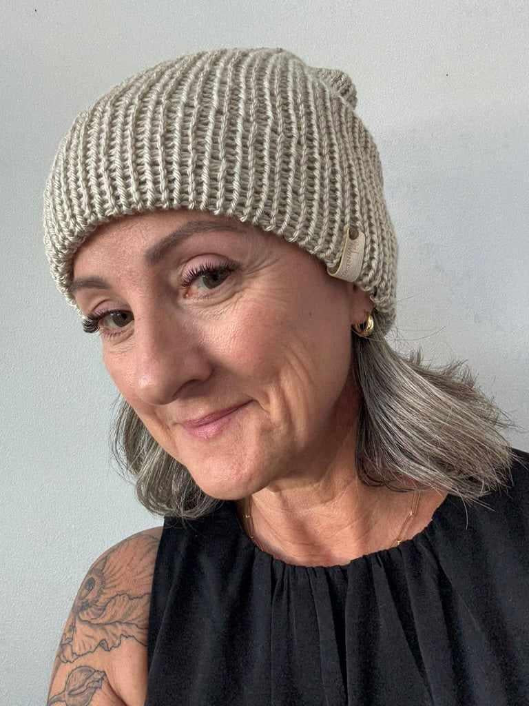 Person wearing a knitted beanie against a plain background