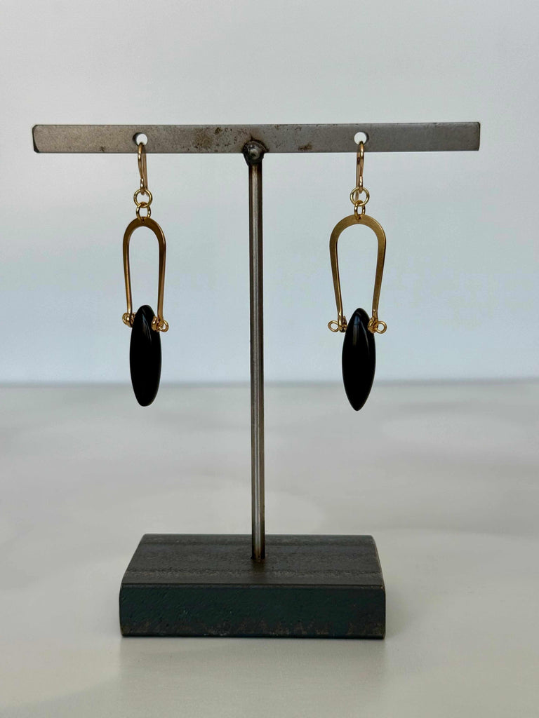 Pair of earrings on a stand with a plain background