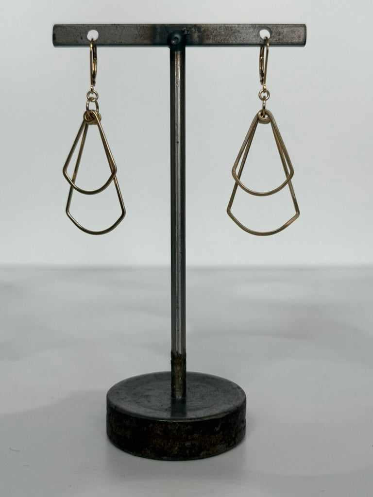 Pair of geometric earrings on a black stand against a white background