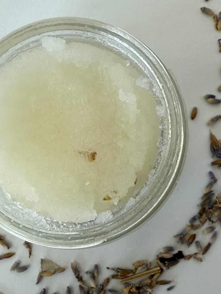 Handmade sugar scrub in a metal container with dried lavender on a white background