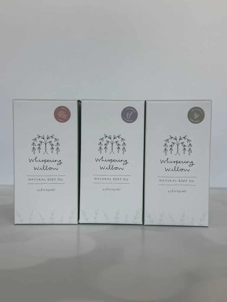 Three boxes of 'Whispering Willow' natural body oil on a white background
