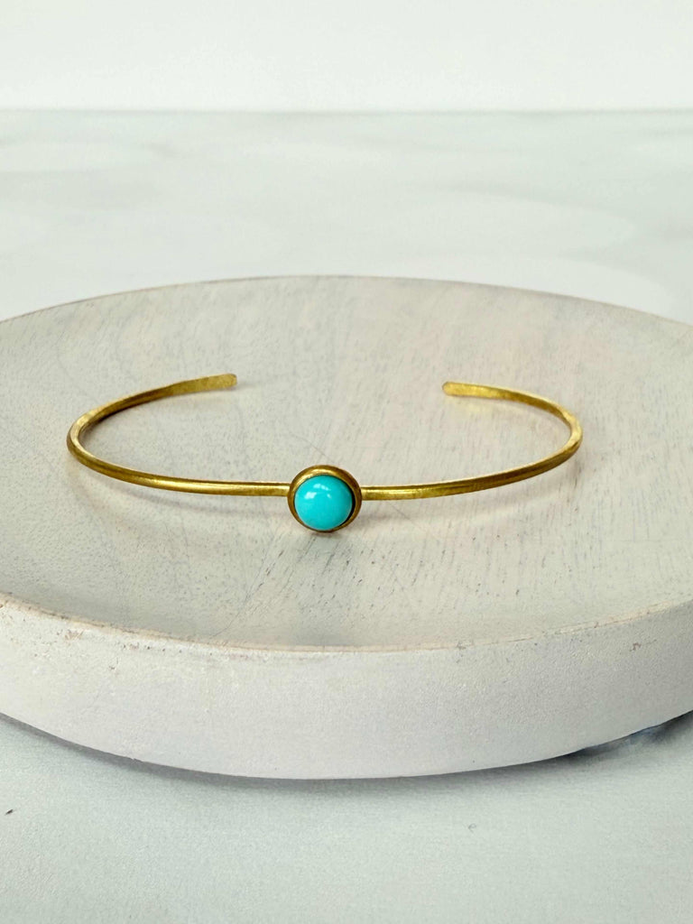 Gold bracelet with a turquoise stone on a white background