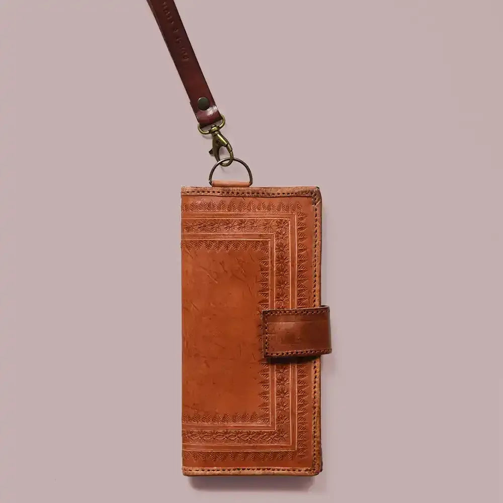 Brown leather wallet with embossed design and lanyard on a beige background
