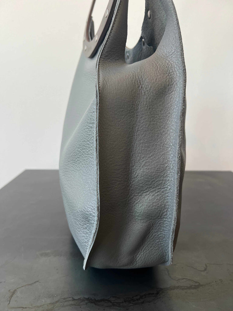 Side of grey and brown teardrop handbag with latigo leather handle