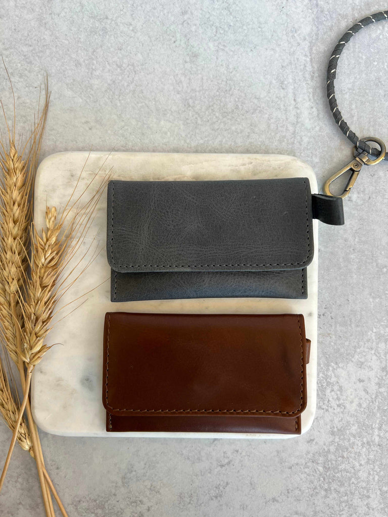 Ethically crafted leather card carriers in black charcoal and chestnut brown with detachable wristlet