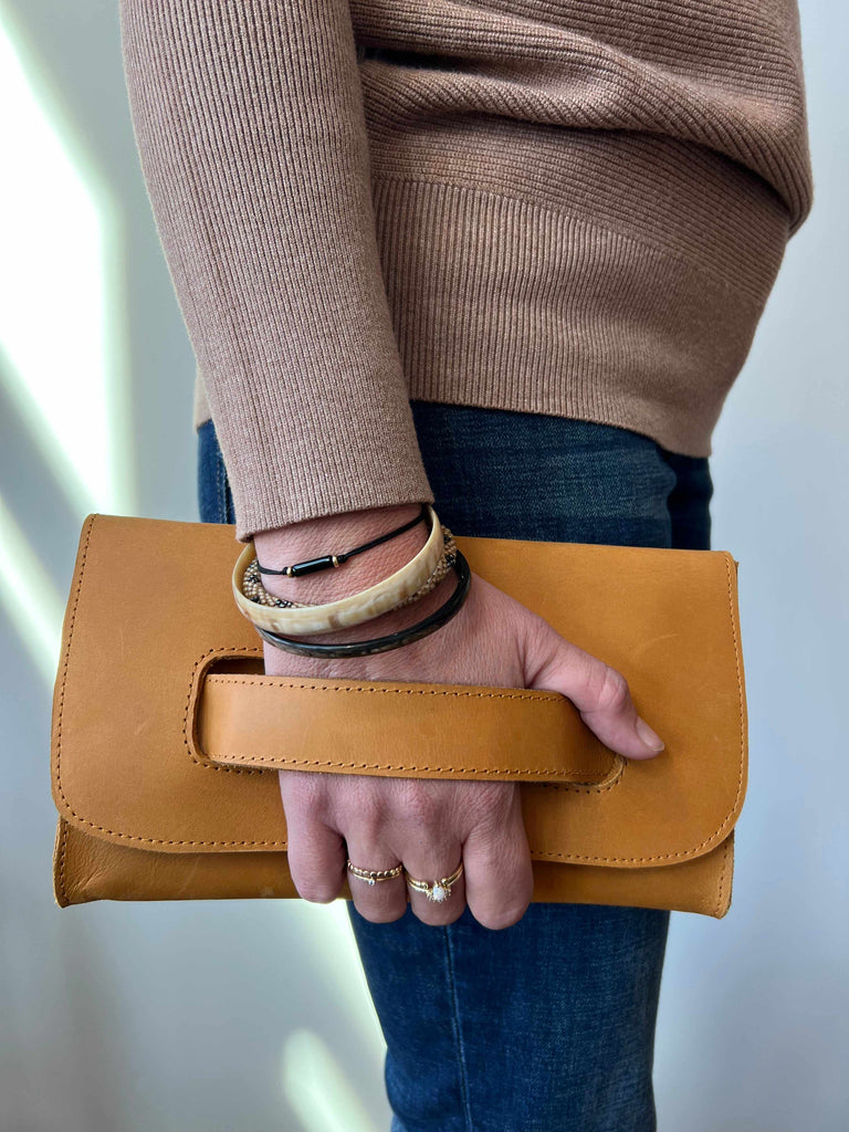 Woman holding leather handle clutch in cognac