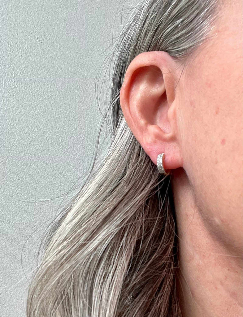 Woman wearing Triple Row Diamond Huggie earrings in sterling silver