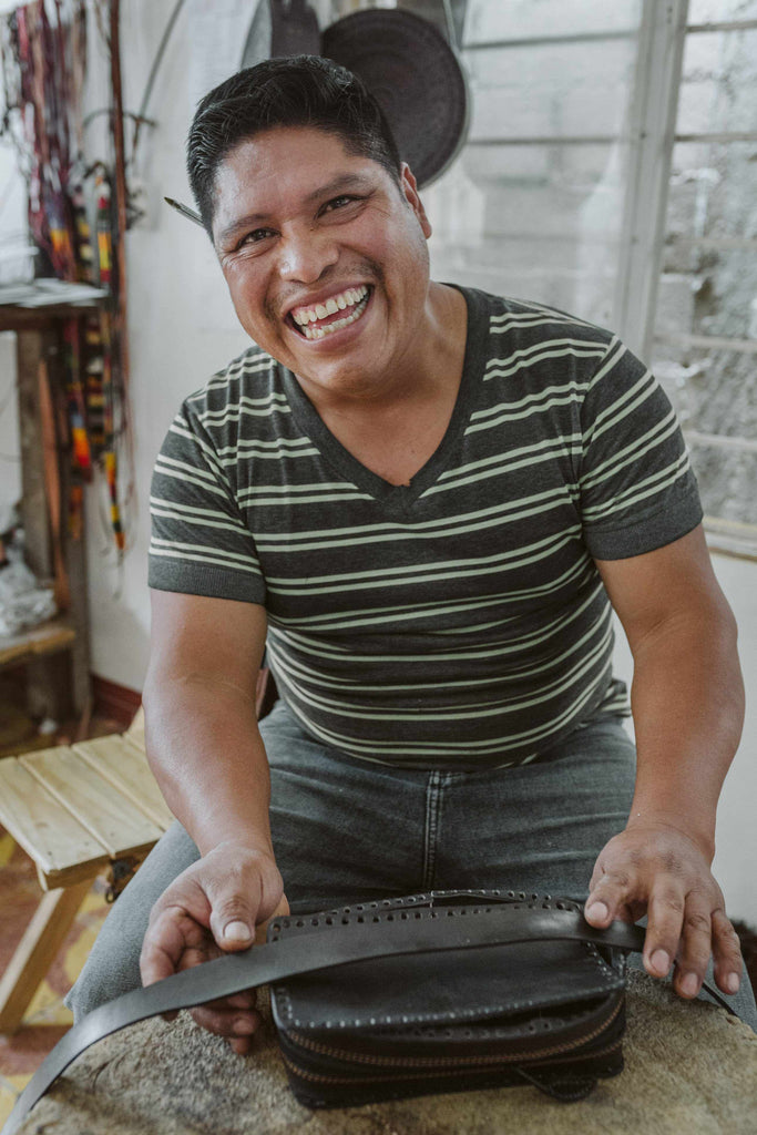 Craftsman smiling while making a leather bag