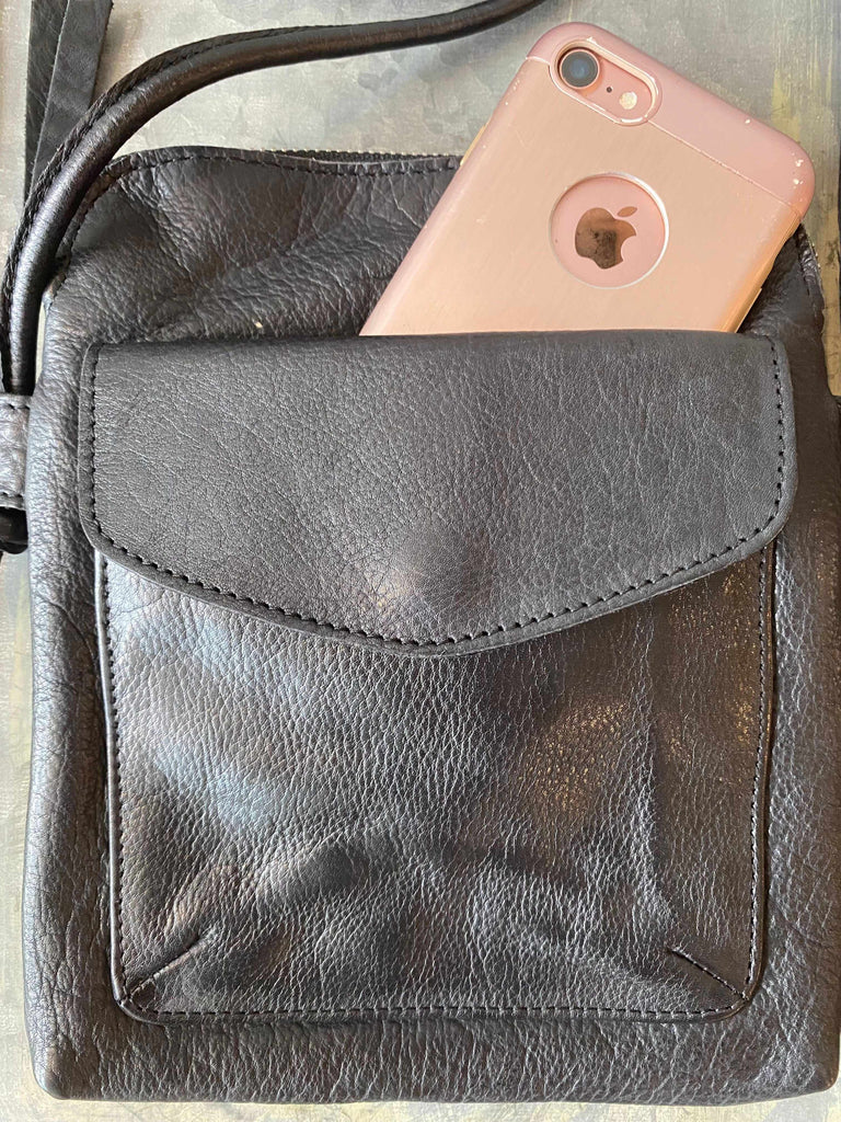 Phone in front pocket of Latico Ezra leather crossbody bag