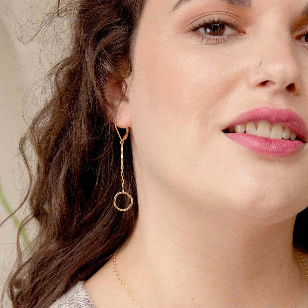 Woman wearing gold dangle hammered circle earrings