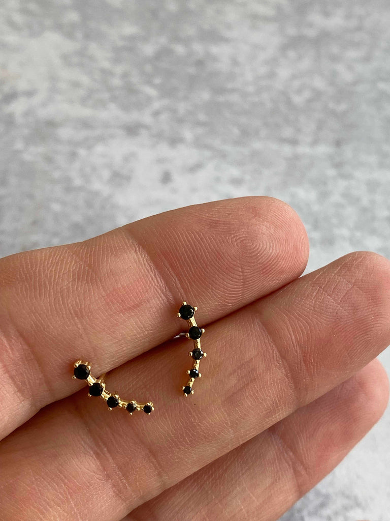 Person holding 18k gold plated sterling silver black crawler earrings