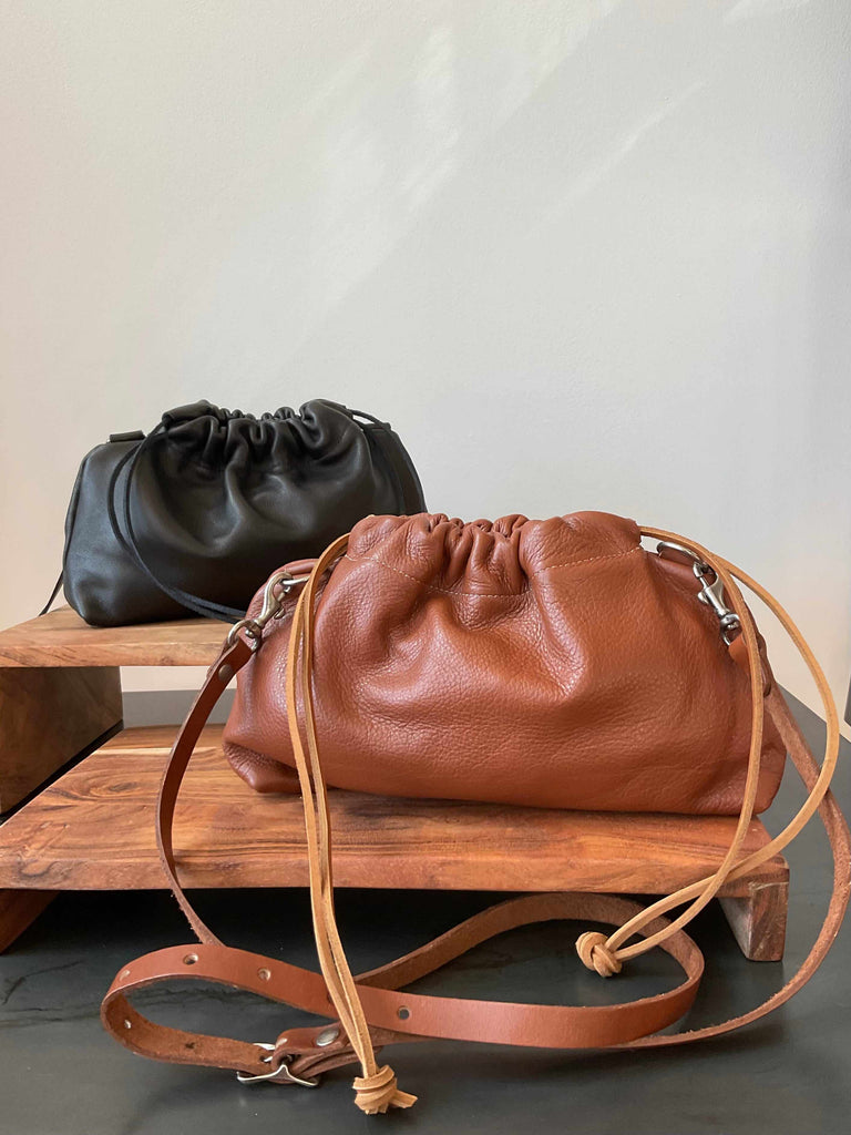Leather crossbody drawstring clutches in black and cognac